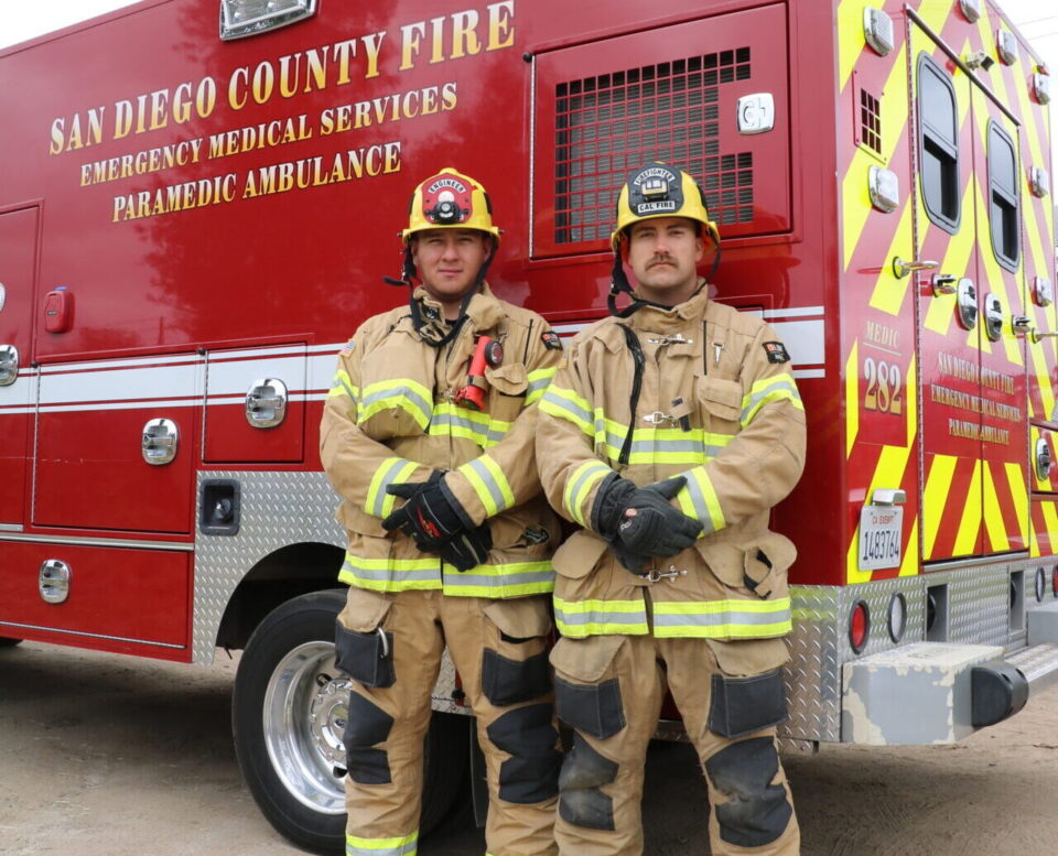 Two firefighter paramedics standing in front of new CAL FIRE red ambulance