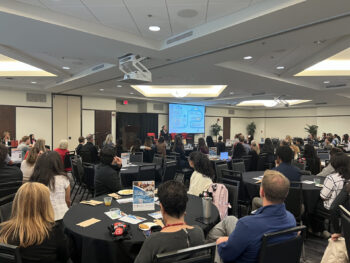 Room full of students listening to speaker and looking at PowerPoint