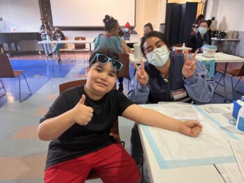 A boy and public health nurse pose following a flu vaccine