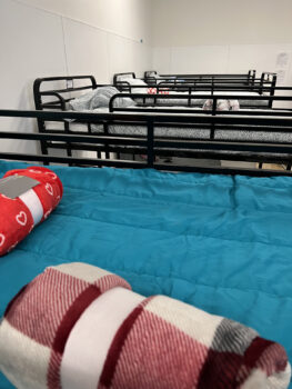 several bunkbeds with rolled up extra blankets on top of the mattress