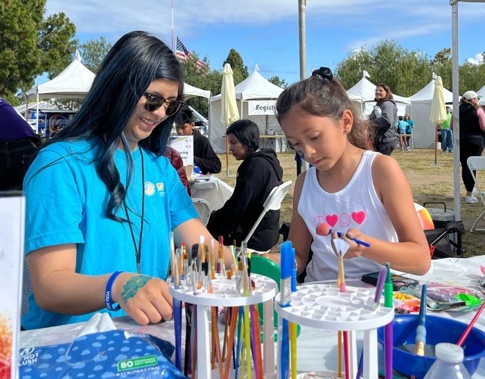 Image from the 2025 NAMIWalks. Woman and small girl sit and paint at a booth