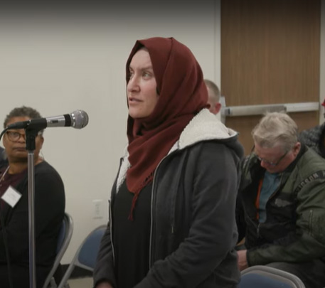 woman stands at microphone at a meeting