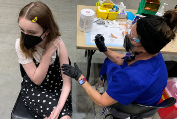A young teenage girl readies herself for her COVID-19 vaccination.