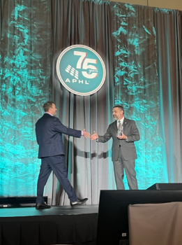 2 men shaking hands on stage with award