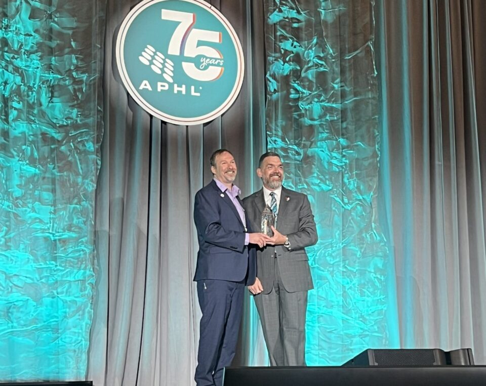 2 men onstage posing with award