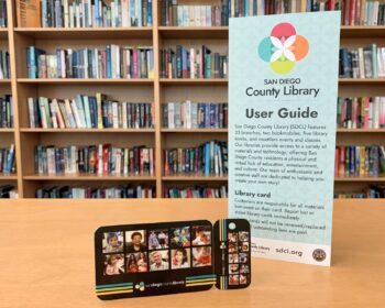 library card and guide on table in front of book shelf