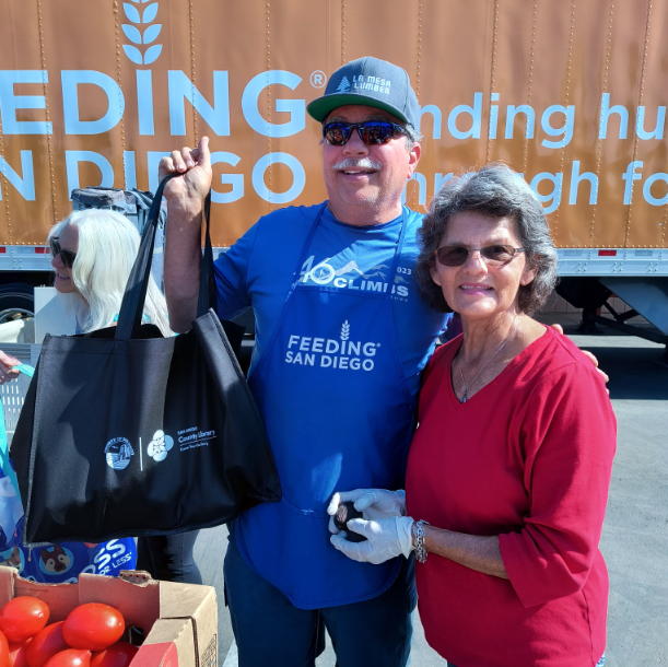 two people stand beside bin on tomatoes