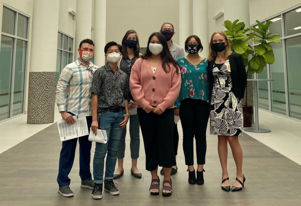 A group of people with masks on stand inside a building