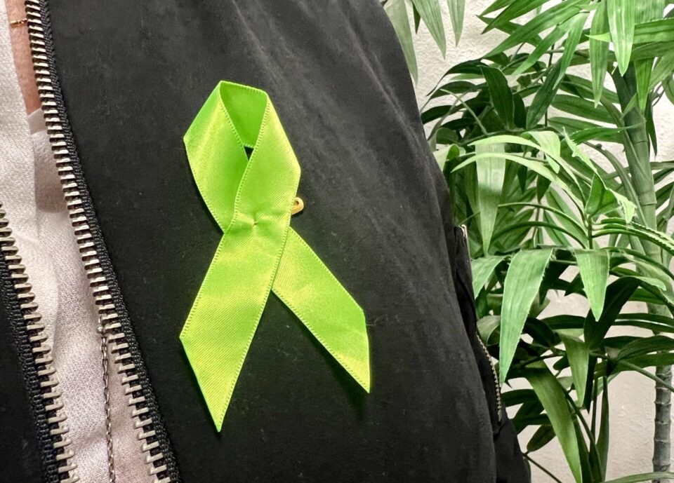 Green Mental Health Awareness Month ribbon in a black jacket