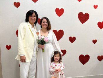 couple and young girl with heart dress stand in front of wall with hearts