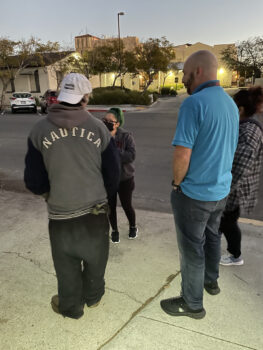 several people speak to one another on the sidewalk
