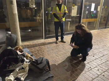 two volunteers speak to a person experiencing homelessness
