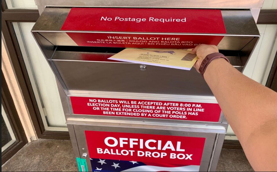 person places ballot into official ballot drop box