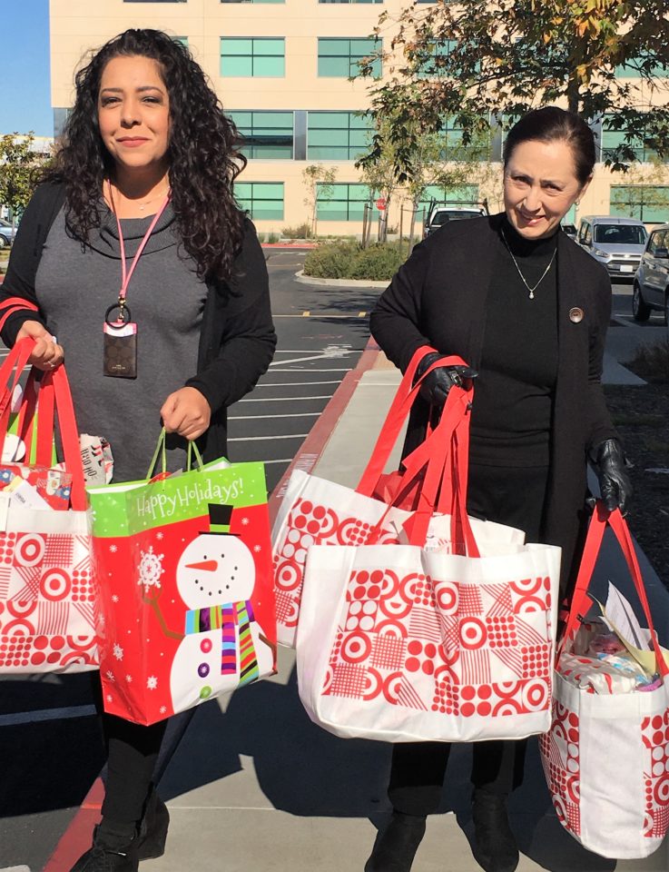 Two women holding several gift bags