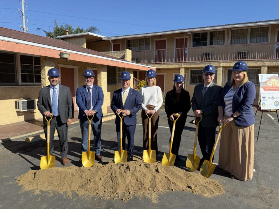 Group with shovels in dirt in front of a motel