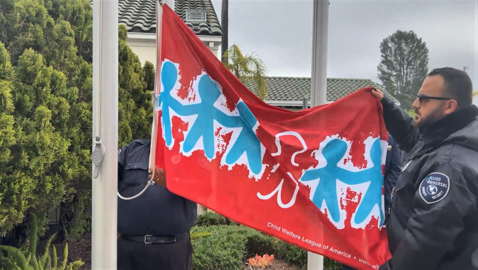 A red and blue banner with the figure of children is raised.