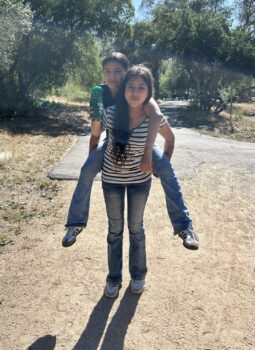 Girl giving piggyback ride to smaller child