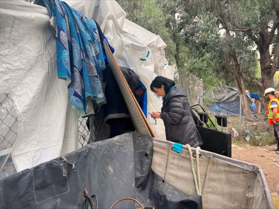 County employee engages with person experiencing homelessness in tent