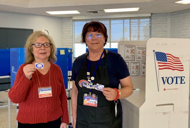 2 poll workers stand in voting center