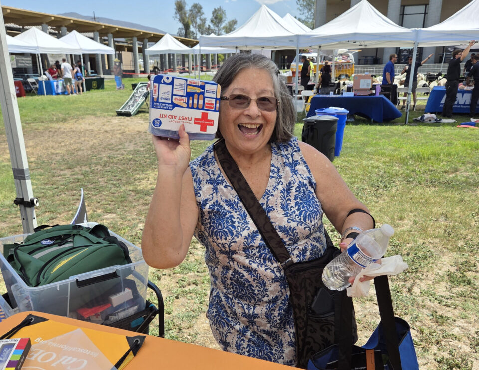 Smiling woman holding first aid kit up