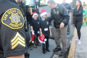 Probation officers assist two children off a bus