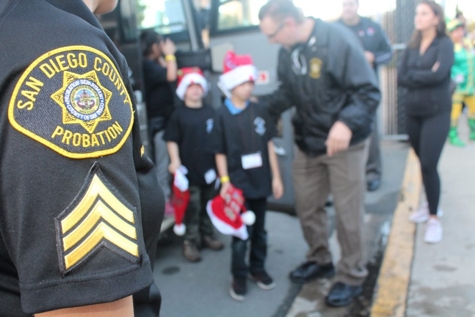 Probation officers assist two children off a bus