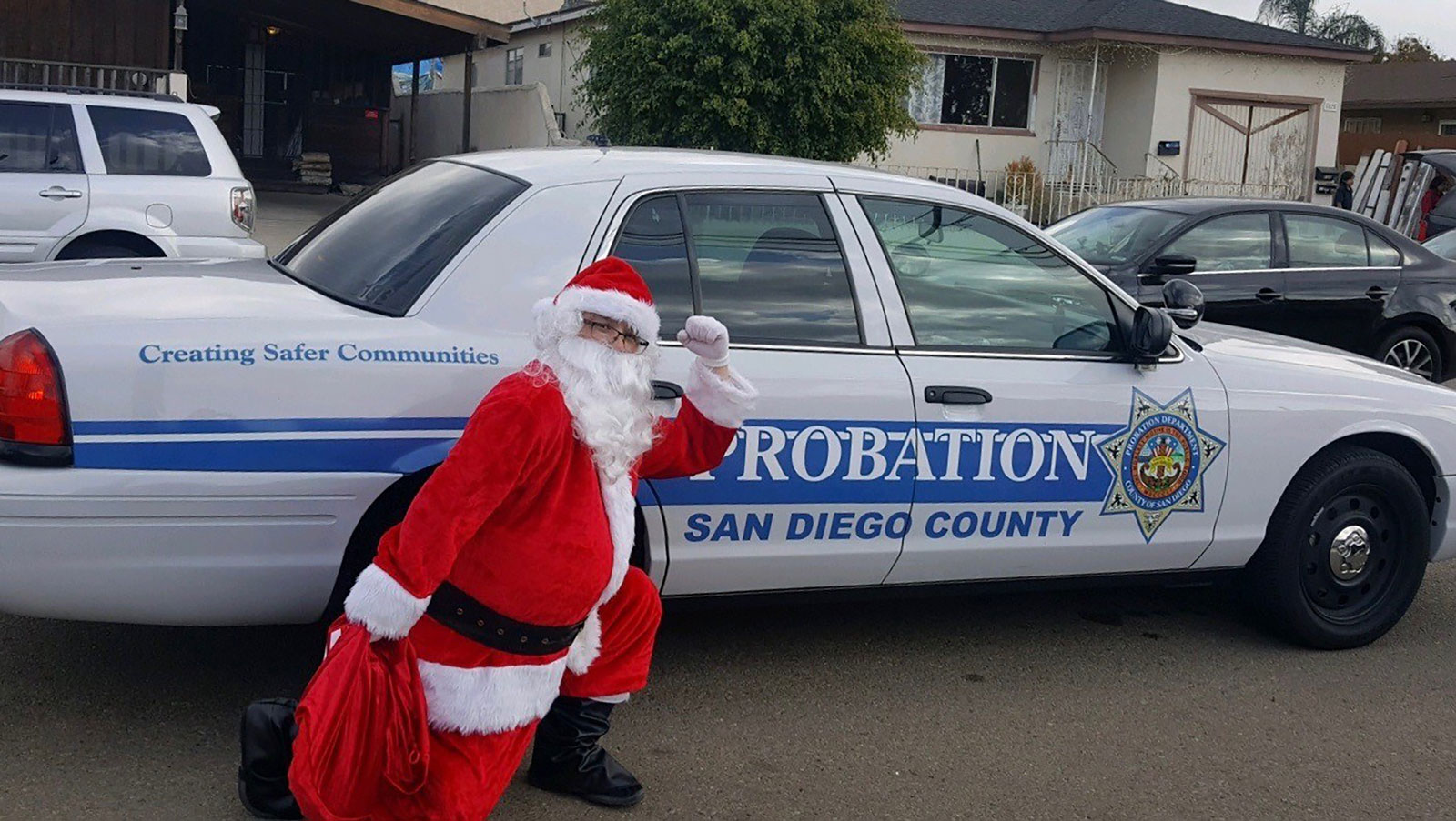 Santa Claus with his toy bag outside a San Diego County Probation car.