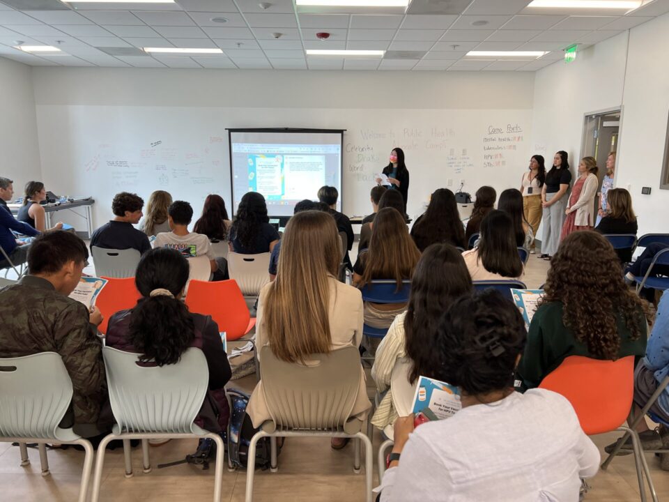 people in classroom face speaker at front of class