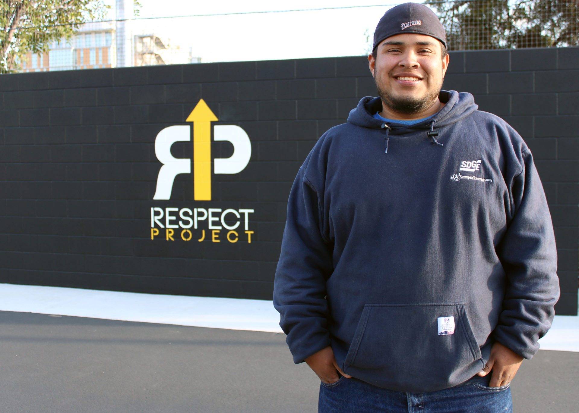 RESPECT Project graduate Antonio Ramirez stands in front of the RESPECT Project logo