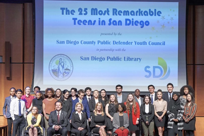 Group photo of 25 teens honored for their accomplishments on stage with award presenters.