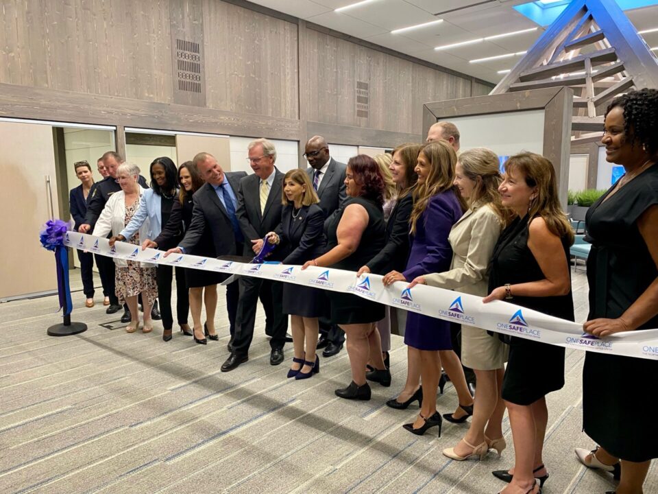 San Diego County Leaders in the lobby of One Safe Place cutting a white ribbon to celebrate the North County family justice center opening