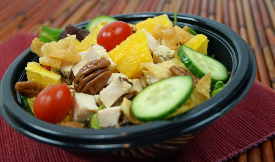 A bowl of salad in a take out container