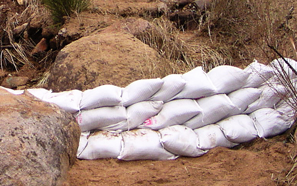 sandbags stacked on a hillside in front of a dirt slope