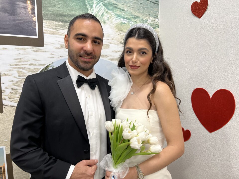 couple stands in front of wall with hearts