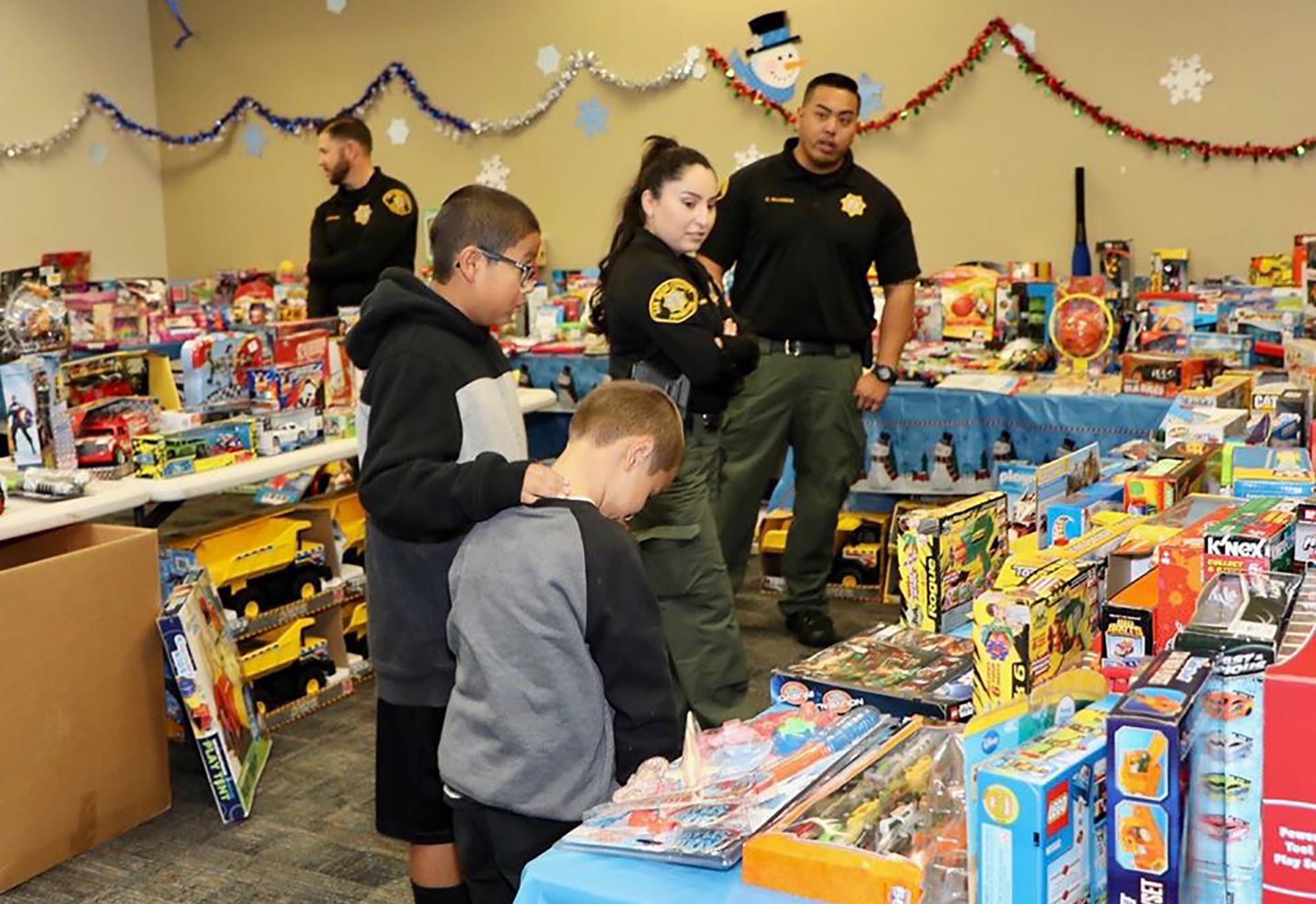 Two young boys select a toy from a toy display and get help from Probation officers.