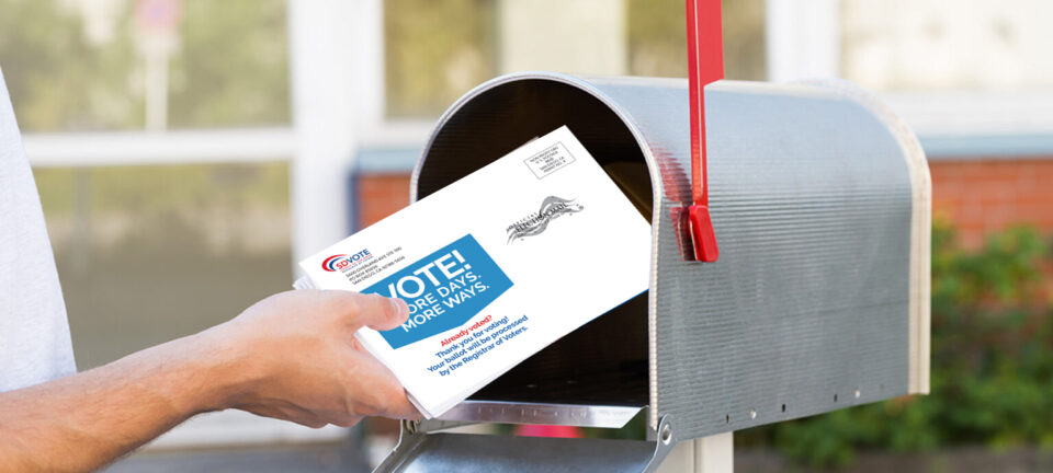 Reminder to vote early postcard going into mailbox