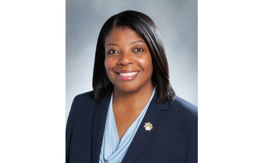 person smiles wearing blue suit and light blue top