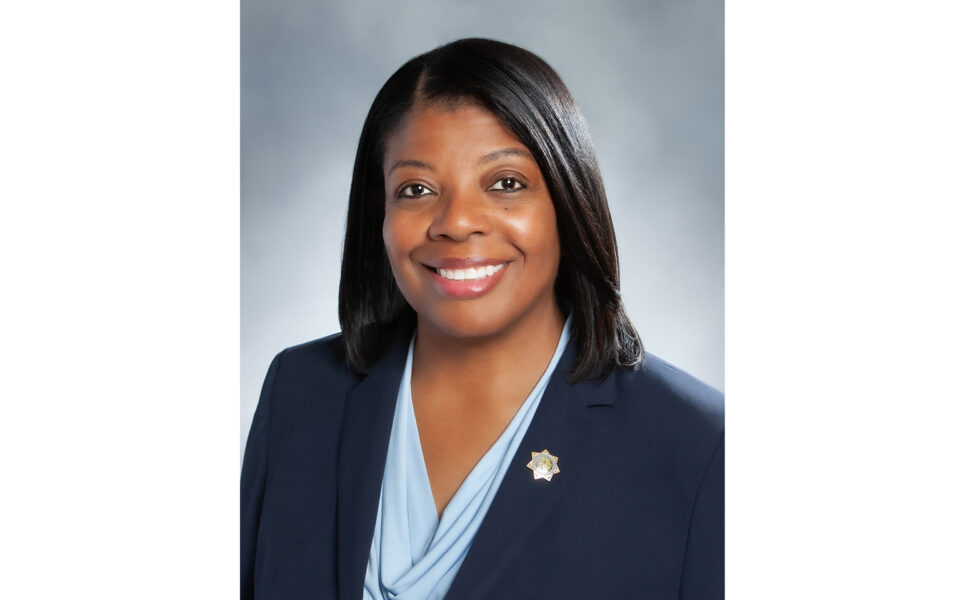 person smiles wearing blue suit and light blue top