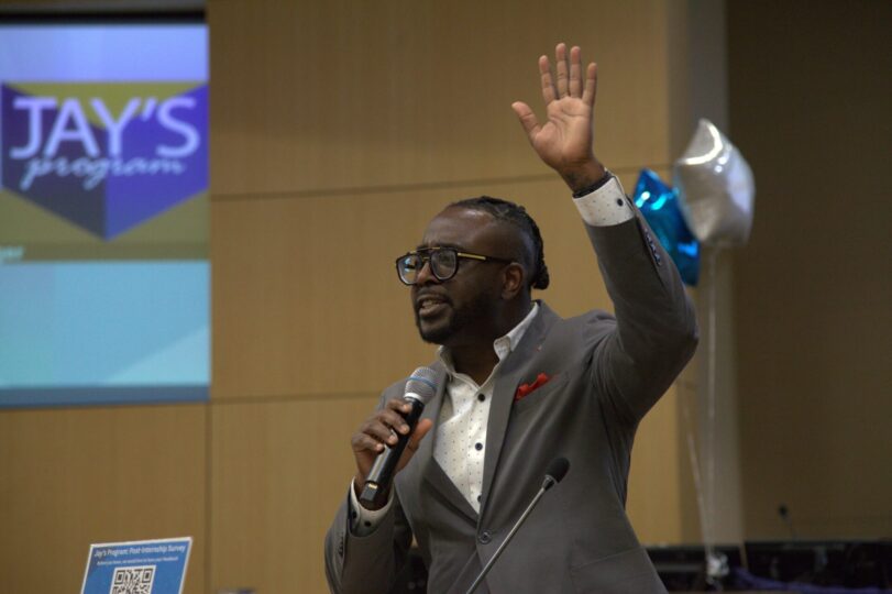 person holds microphone and raises hand at graduation ceremony