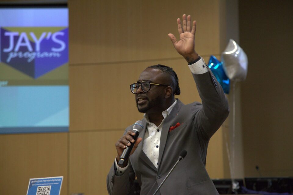 person holds microphone and raises hand at graduation ceremony