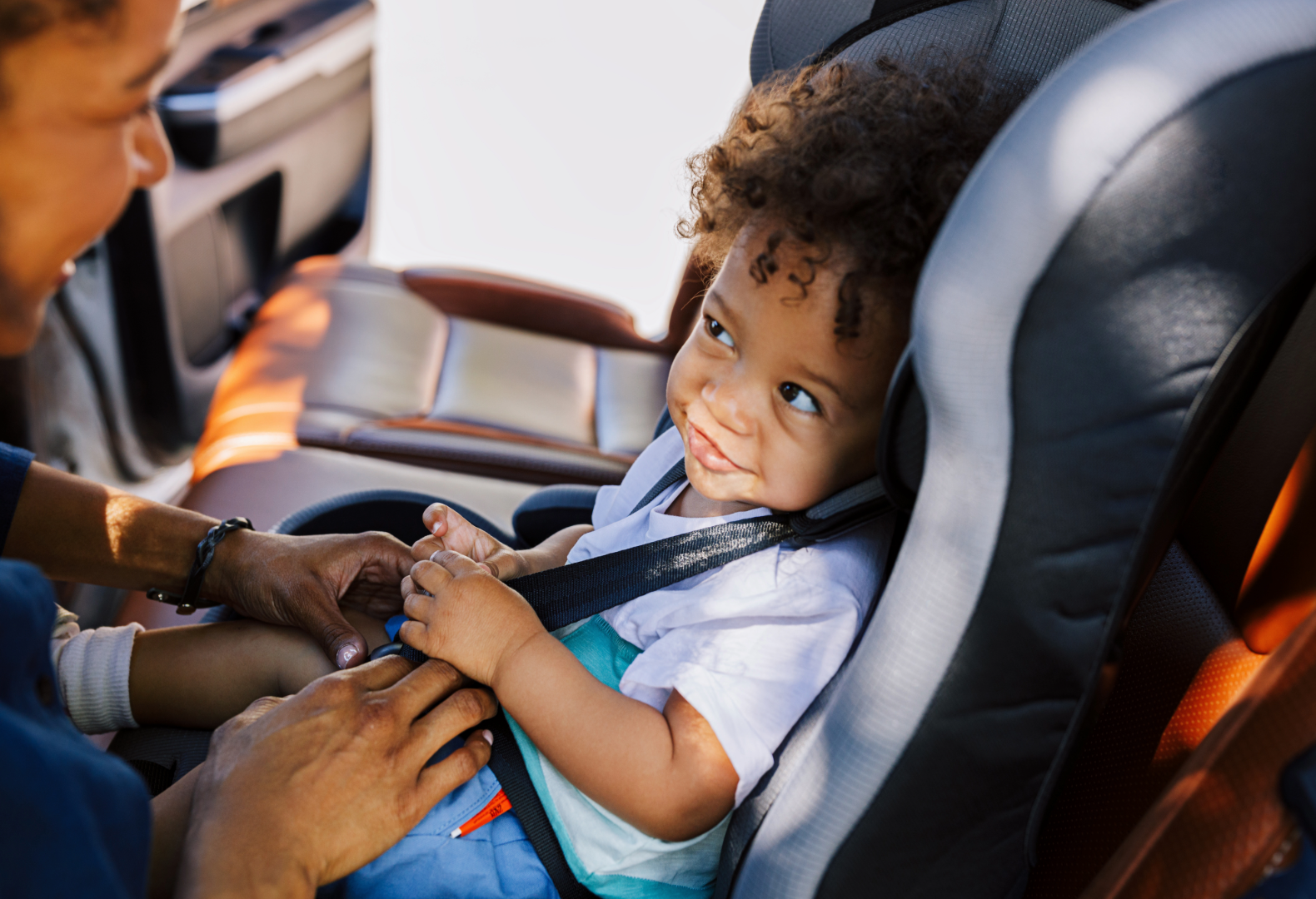 Mom buckling in toddler into car seat