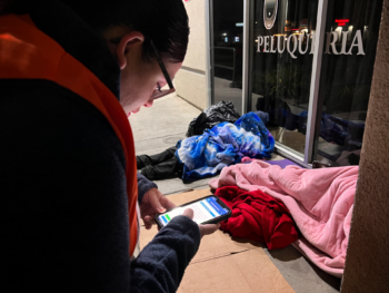 Volunteer holds phone to log survey with person experiencing homelessness