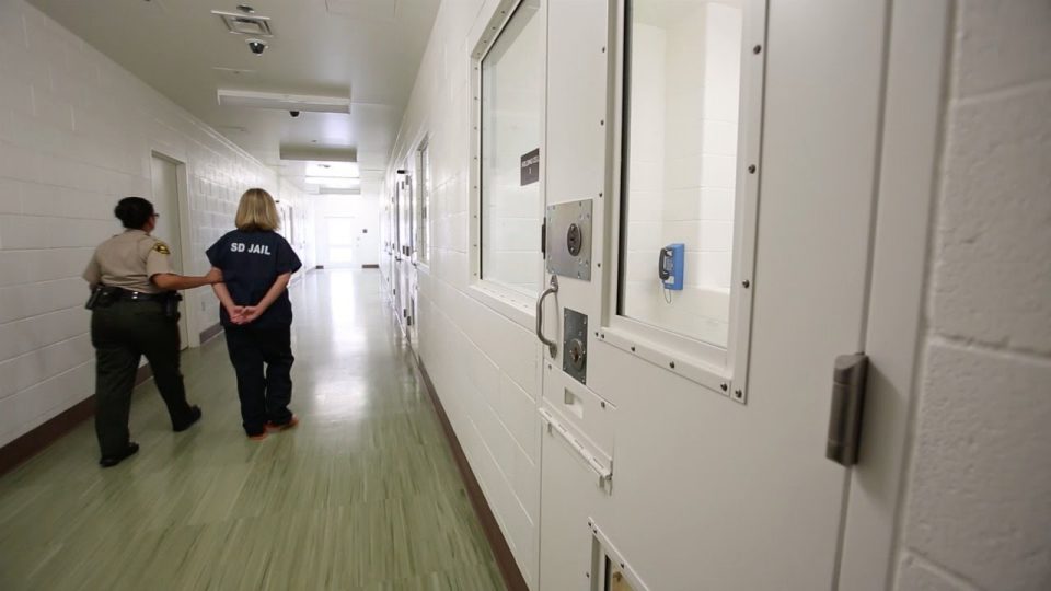 A woman being walked down a hallway at Las Colinas Jail