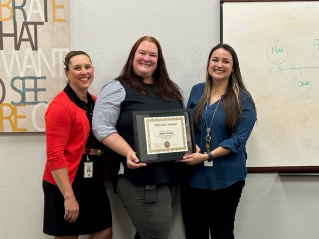 Three women standing holding plaque for Child Welfare Services Director's Award.