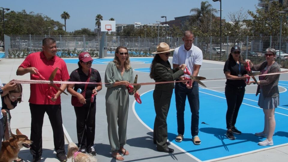 people cut a giant ribbon on an outdoor basketball court