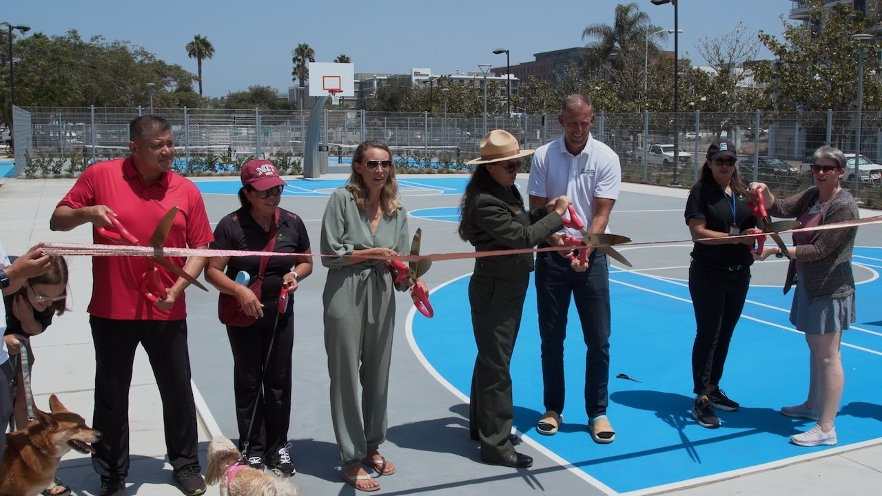 people cut a giant ribbon on an outdoor basketball court