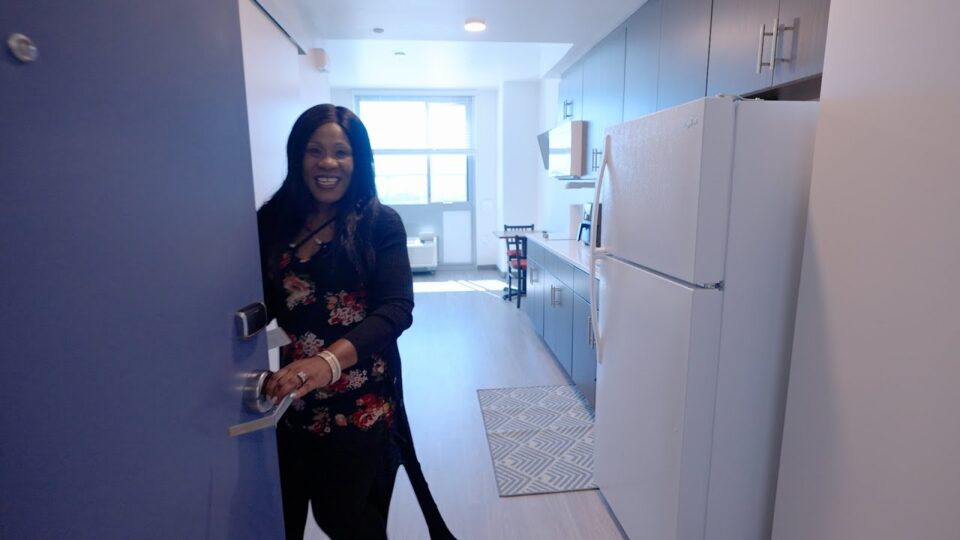 woman stands at door to apartment