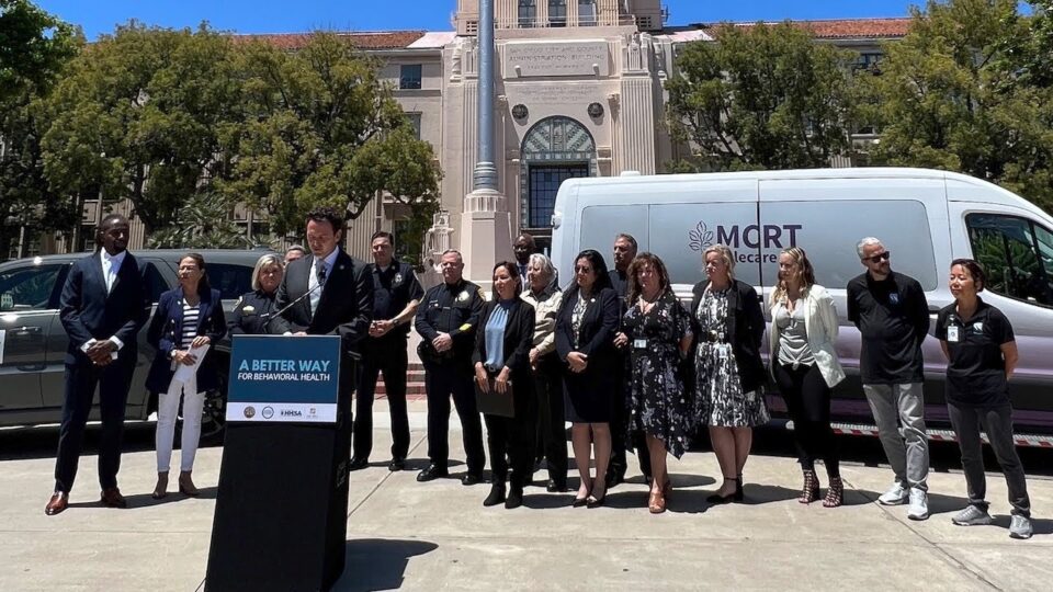 a group of people stand front of a the CAC as Chair Fletcher speaks