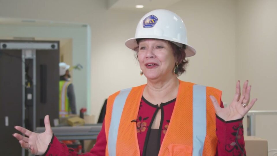 person wearing hard hat talks with hands