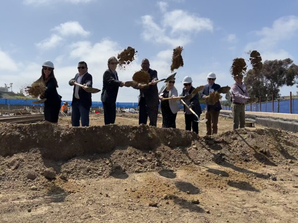 Dignitaries with shovels throwing dirt.